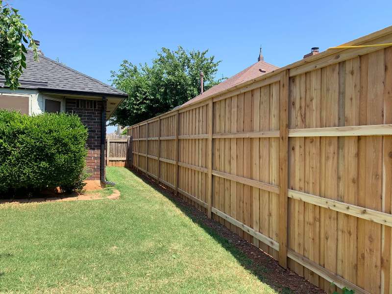 Stockade style privacy fence built using pressure-treated lumber.